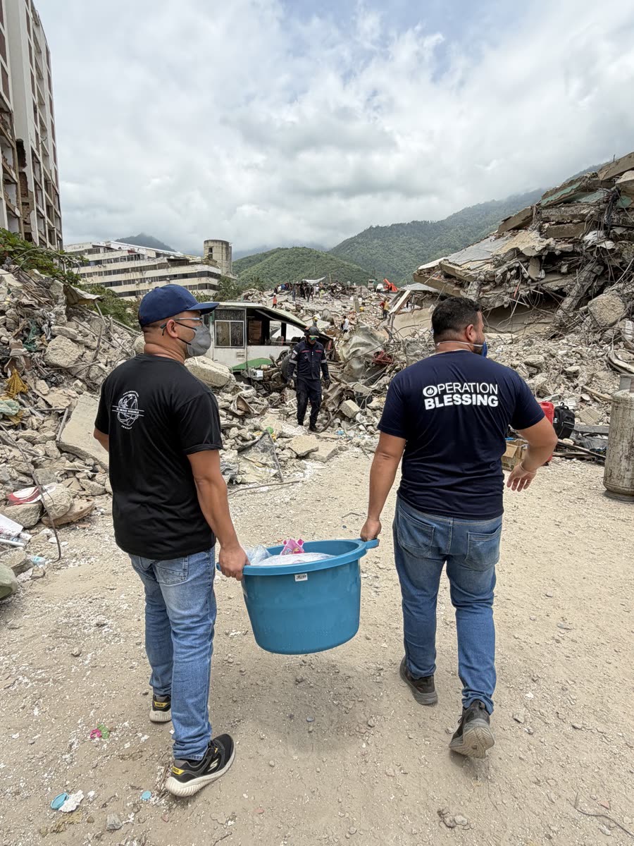 Voluntários levando suprimentos entre os escombros
